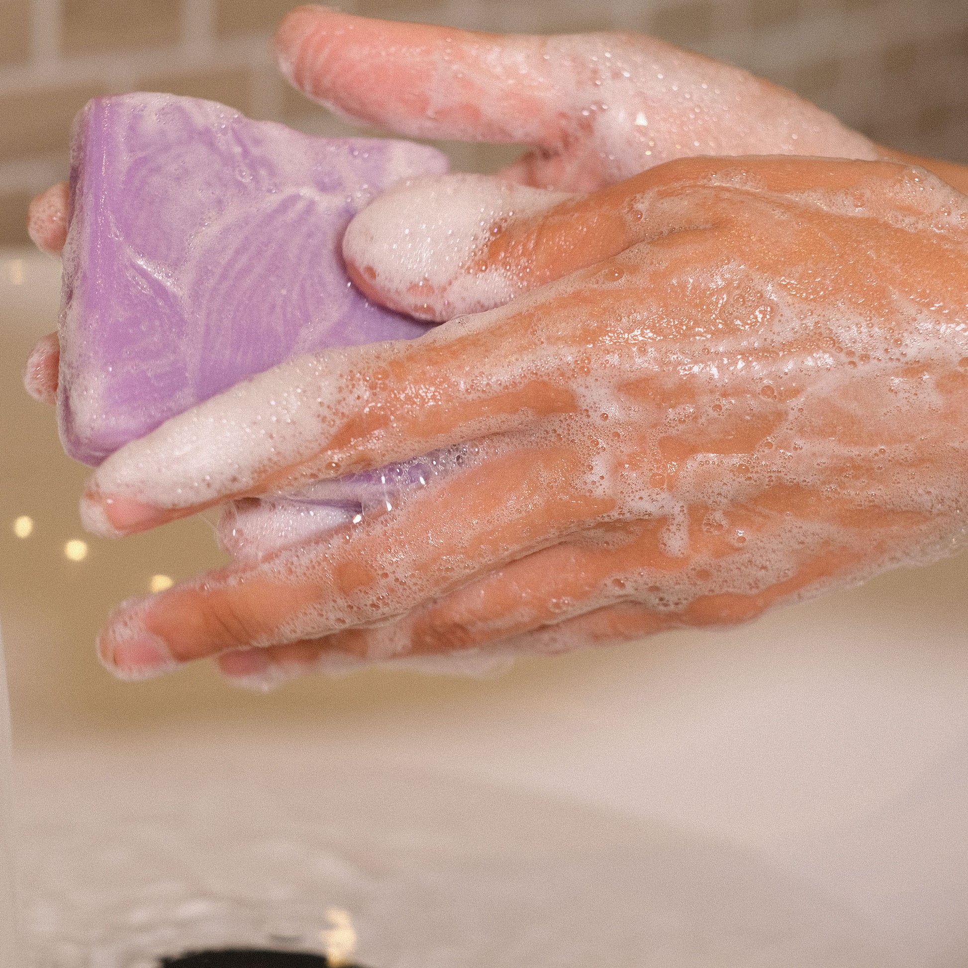 Naturseife Lavendella beim Händewaschen unter einem Wasserstrahl mit Schaum an den Händen