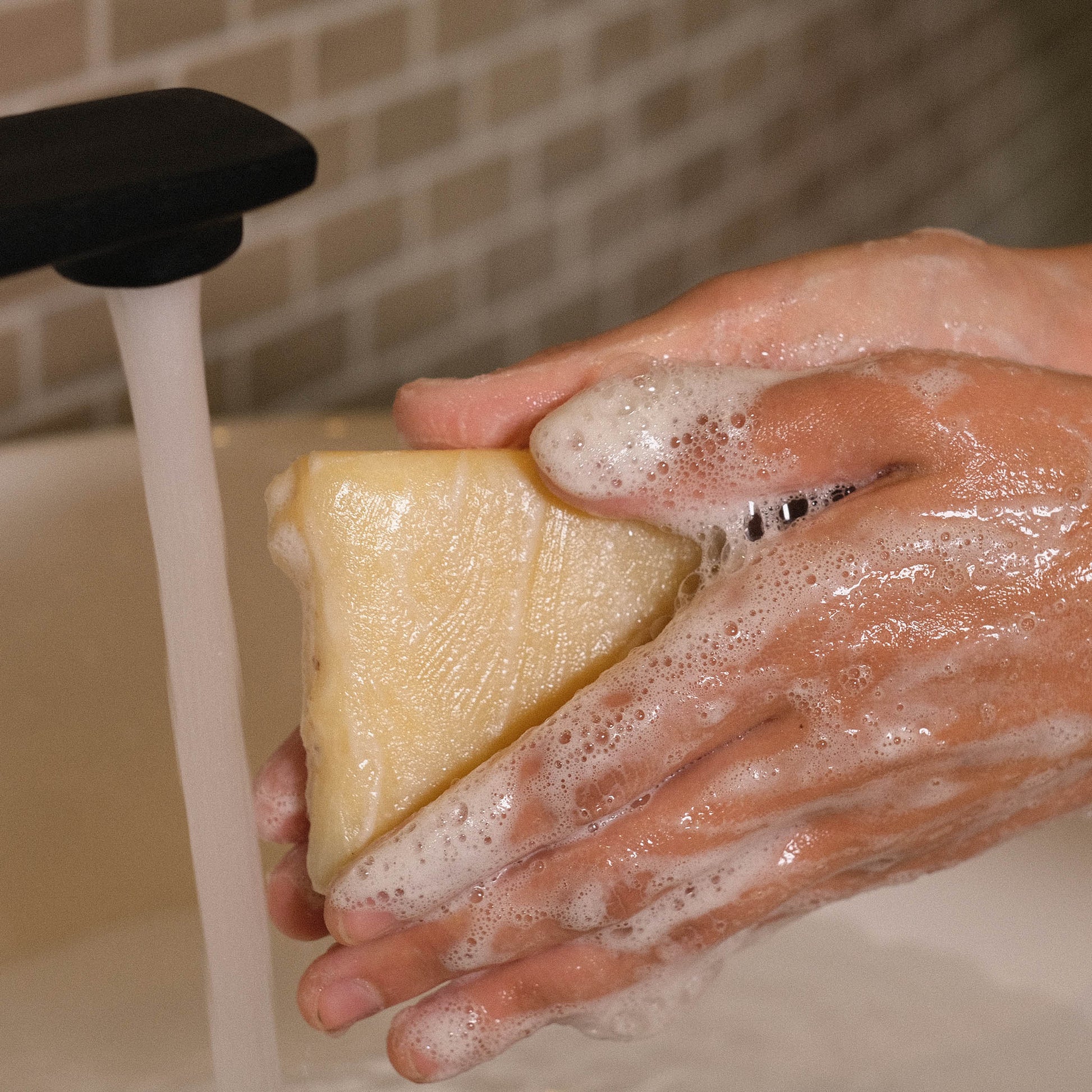 Naturseife Natura beim Händewaschen unter einem Wasserstrahl mit Schaum an den Händen