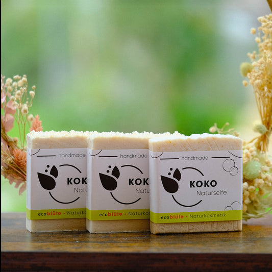 Naturseife KOKO mit Banderole, handgemacht in unserer Seifenmanufaktur, eine Peelingseife die nach Kokos duftet. 3er Set mit Gesteck
